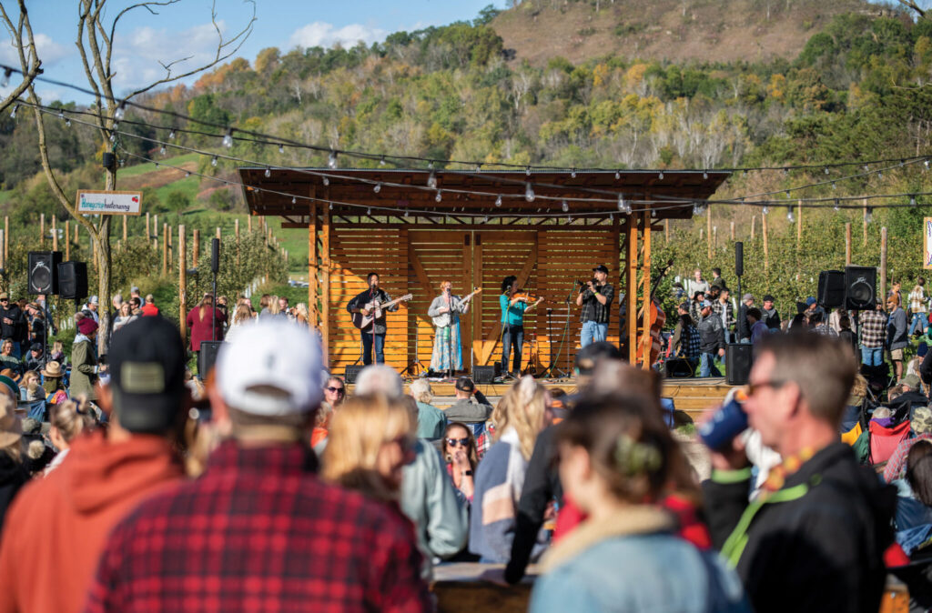 A band performs on a wooden outdoor stage at Ecker's Apple Farm.