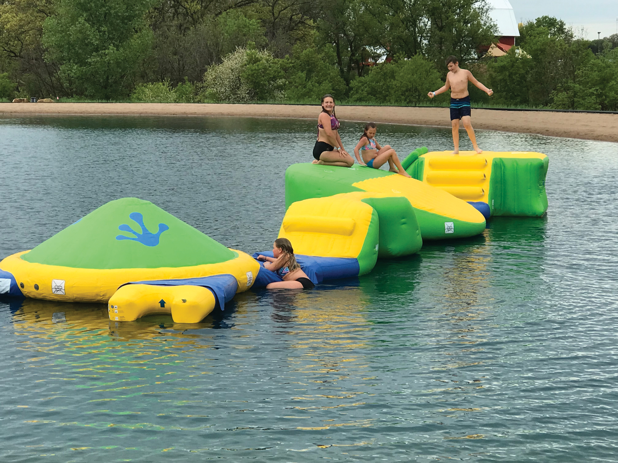 Photo of three children bouncing on large inflatables on a river
