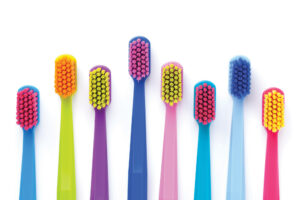 A flatlay of eight brightly colored toothbrushes