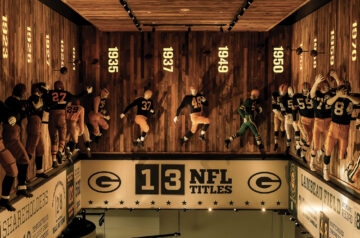 Green Bay Packers Hall of Fame exhibit showcasing life-sized player mannequins, historical years, and team achievements displayed on wooden walls.