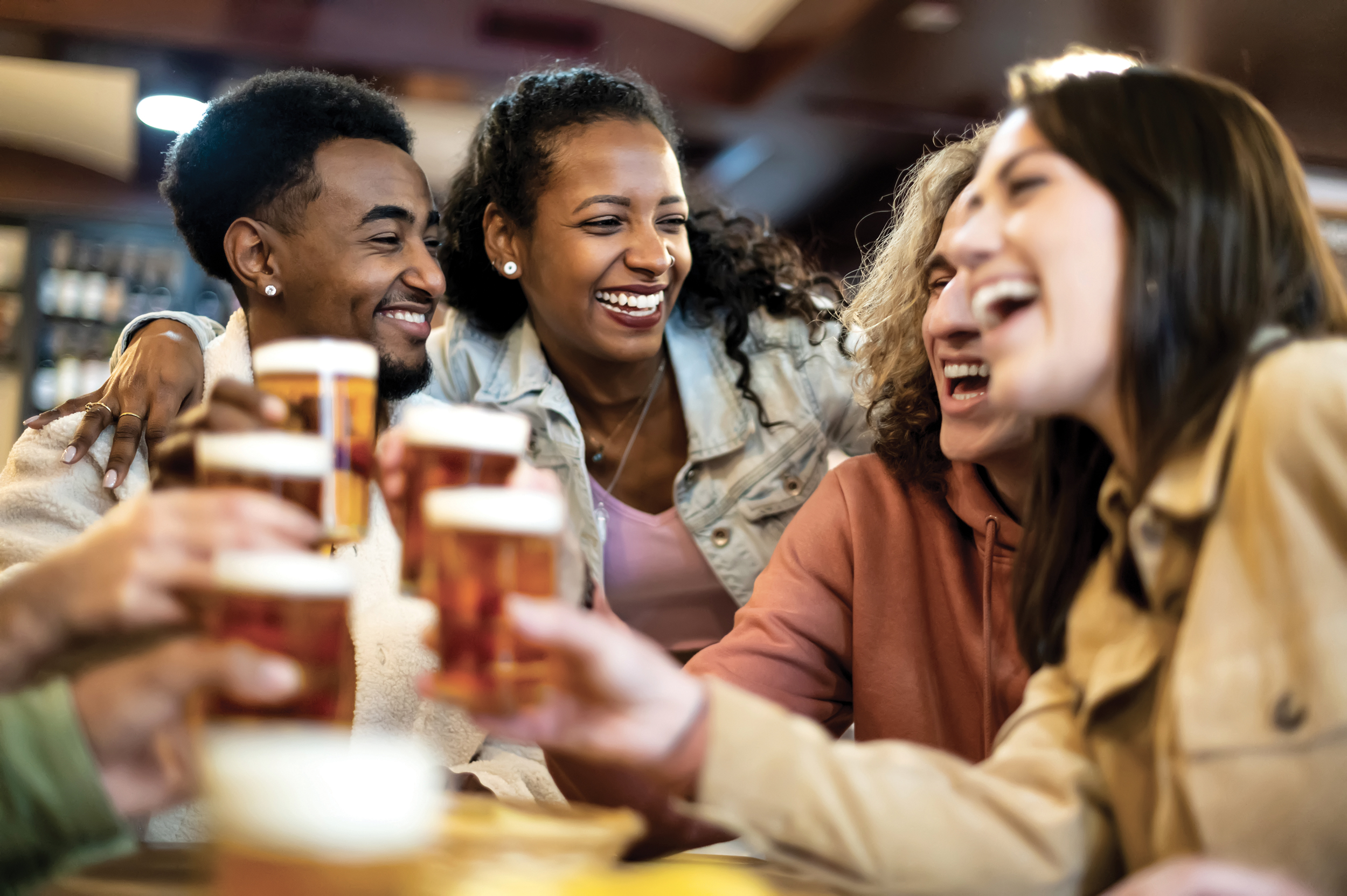 Photo of several young people laughing and toasting with a half pint of beer