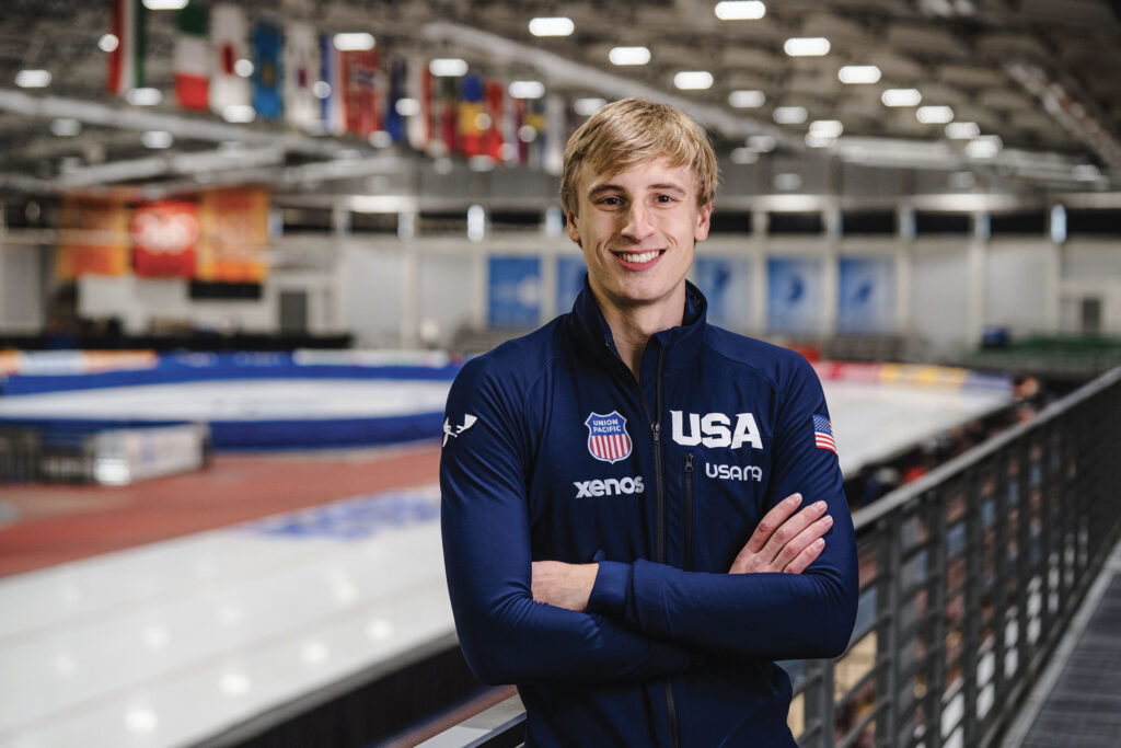 Portrait of 21-year-old long track speedskater Jordan Stolz in his USA uniform in front of the ice rink.