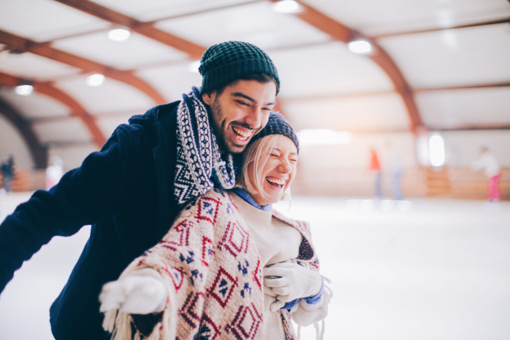 A couple skates indoors on the ice