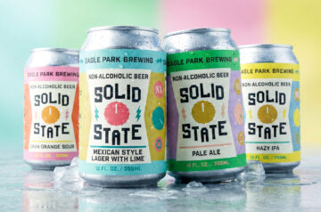 Four chilled cans of Eagle Park Brewing’s Solid State non-alcoholic beer series—Mexican-style lager with lime, pale ale, hazy IPA, and cranberry-orange sour—arranged on ice with visible condensation, set against a softly blurred pastel backdrop divided into vertical bands of mint green, pale pink, light yellow, and sky blue.