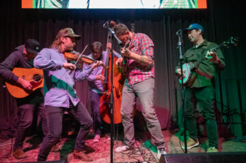 The MilBillies gather on the stage and play toward one another at the Bluegrass Winter Heater at The Cooperage.