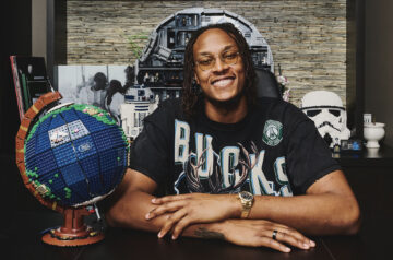 Photo of Milwaukee Bucks Myles Turner surrounded by his lego creations including a globe, pac man, cat, and storm trooper helmet.