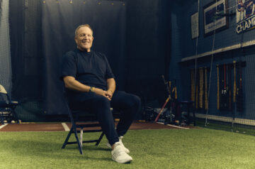 Milwaukee Brewers Head Coach Pat Murphy sitting on a fold out chair surrounded by baseball memorabilia.