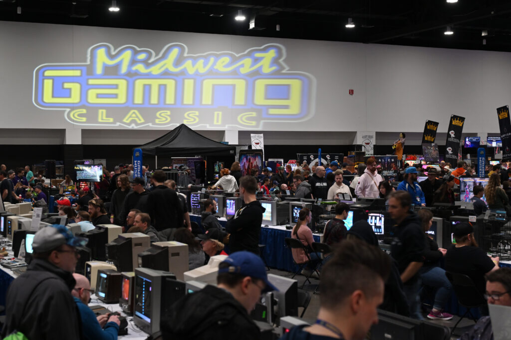 A photo showing people playing on computer setups in a convention center