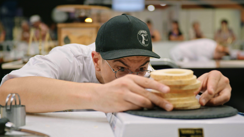 A cheesemonger inspects a pile of cheese during a competition.