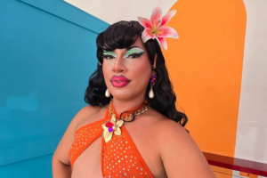 Milwaukee drag queen Susie Starlet posing with a flower in her hair and an orange dress.
