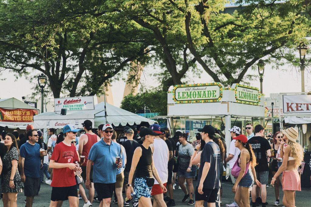 A crowd at Summerfest walks past food stands.