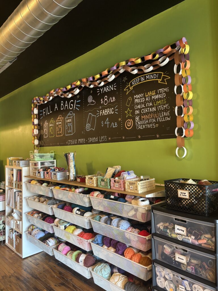 A chalkboard listing prices above baskets of crafts at 414 Art Revival.