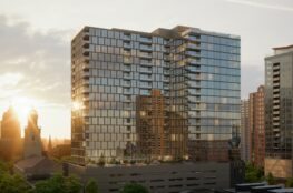 Architectural rendering of a modern glass residential tower rising above a multi-level podium, reflecting the surrounding downtown skyline at sunset, with historic church towers and neighboring high-rise buildings visible in the background.