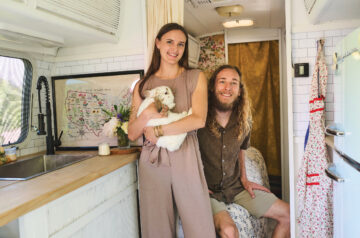 A smiling young couple posed with a rabbit inside a camper.