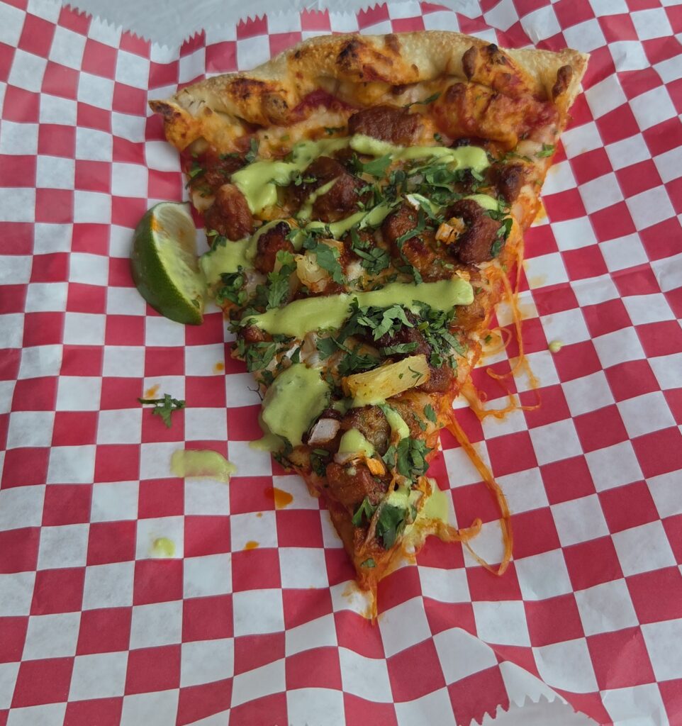 A slice of al pastor pizza on a lunch plate.