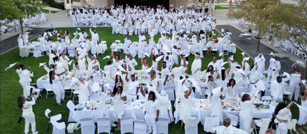Crowd waving napkins all dressed in white.