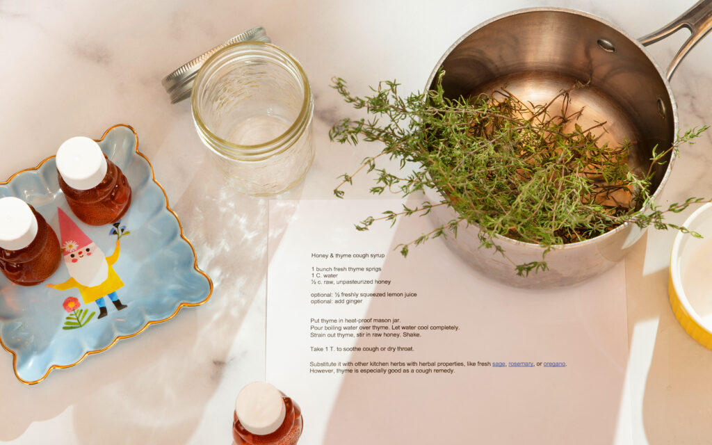 Garden thyme in a pot used to make cough syrup with the recipe next to it on a counter.