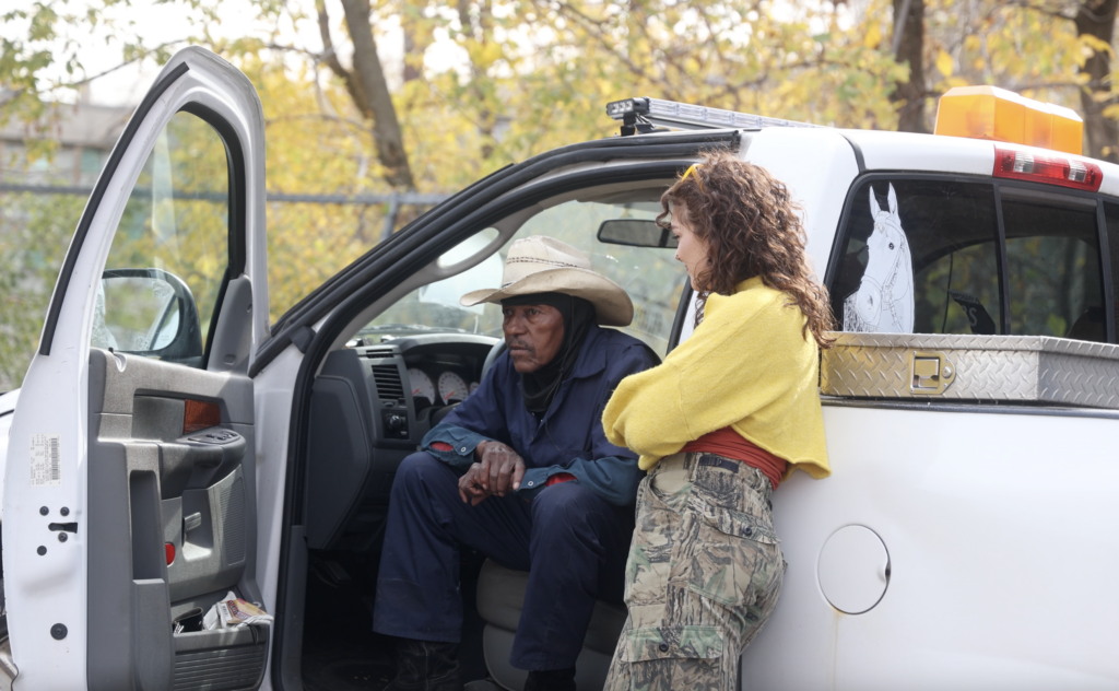 Issac Steele, wearing a cowboy hat, speaks with filmmaker Natalie Derr.