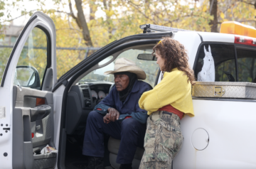 Issac Steele, wearing a cowboy hat, speaks with filmmaker Natalie Derr.