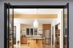 In the kitchen, original sliding glass doors were replaced with 9-foot-tall folding glass doors, further connecting the space with the interior courtyard. Tempesta quartzite countertops were a bold choice but pair beautifully with the custom walnut cabinetry. Above the island, the Japanese styling of a pair of Muuto pendant lights enhances the aesthetic of the space. Photo by Kevin J. Miyazaki